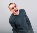 Angry young man shouting with open mouth and very anger face, showing the fists in fashion glasses Royalty Free Stock Photo