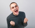 Angry young man shouting with open mouth and very anger face, showing the fists in fashion glasses Royalty Free Stock Photo