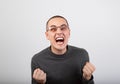 Angry young man shouting with open mouth and very anger face, showing the fists in fashion glasses Royalty Free Stock Photo