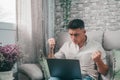 Angry young man using computer pc at home sitting on the sofa having problems with technology. Mad boy with laptop watching a Royalty Free Stock Photo