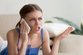 Angry young woman arguing talking on cell phone at home