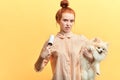 Angry young woman with hairbun is using a lint roller to remove the hairs