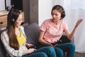 angry young woman in headphones with joystick in hand quarreling with female friend