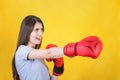 Angry young woman with red boxing gloves stands in fighting position, punching with hand. Portrait of strong and determined girl Royalty Free Stock Photo