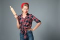 Angry young woman with rolling pin on grey background Royalty Free Stock Photo