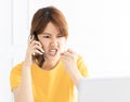 Angry young woman  shouting on mobile phone while working on  laptop Royalty Free Stock Photo