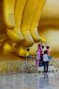 Buddists touching end of finger of large golden Buddha image