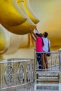 Buddists touching end of finger of large golden Buddha image