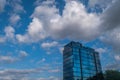 Angular geometric mirror cladding on a modern building with repeating structure and reflected sky and clouds