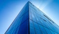 Angular glass skyscraper with sun peeking from behind against a vivid blue sky low angle Royalty Free Stock Photo