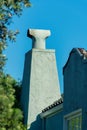 Angular square chimney with metal vent ontop with back or front yard trees with stucco or cement blue exterior Royalty Free Stock Photo