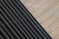 Angular view close-up of dark metal beams structure in part of building and smooth beige tiled wall