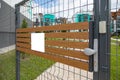 Angular view of metal gates with blank tablet on wooden planks