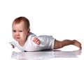 Angy upset infant baby boy toddler in diaper and white bodysuit is lying on floor on his stomach holding hands up Royalty Free Stock Photo