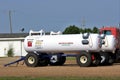 Anhydrous Ammonia tanks in a farm yard with a building,truck and blue sky out in the country.