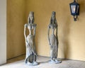 Anicent stone sculptures of female royalty stadning in Dallas, Texas, beside a gothic style wall lamp.