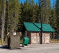 An animal proof garbage dumpster and a public bathroom facility at a rest stop in Field, British Columbia, Canada