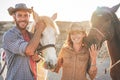 Animals lovers couple taking with bitless horses during sunny day inside ranch corral - Happy people having fun training at their Royalty Free Stock Photo