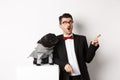 Animals, party and celebration concept. Amazed young man and black dog in costumes staring right at copy space, standing Royalty Free Stock Photo