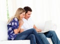 Animated couple using a laptop sitting on sofa Royalty Free Stock Photo