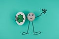 Animated drawing pebble, greeting all and holds one cracked egg with electronic circuit inside, on blue paper background Royalty Free Stock Photo