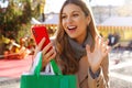 Animated girl say hello in video calling with telephone carrying shopping bags on Christmas time outdoors Royalty Free Stock Photo