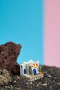 Animated model of a Greek house on a rock on a neon and pink background.