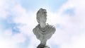 Animation of gray sculpture of man over blue sky and clouds