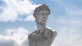 Animation of gray sculpture of man over blue sky and clouds