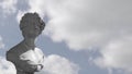 Animation of gray sculpture of man over blue sky and clouds, copy space