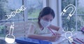 Animation of school icons over focused caucasian girl wearing face masks doing homework