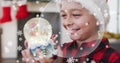 Animation of snow falling at chrsitmas over happy caucasian boy with snow globe