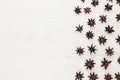 Anise stars spice pattern on white wood background.