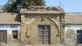 A ruined stone structure with a wooden door in the town of Anjar in Kutch