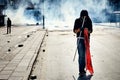 Young male protester holding a flag walks on the street covered by tear gas fired by the police during Gezi park protests in