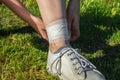 Ankle sprain, woman bandages her leg while walking on a summer nature. Concept of tired legs, injury on running Royalty Free Stock Photo