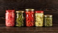 ÃÂ¡anned vegetables in glass jars on a dark wooden shelf. Preserved artichoke in oil, pickled ginger, gherkins, capers and small Royalty Free Stock Photo