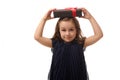 Winsome smiling little girl in evening dress holding a black gift box with red ribbon on her head, looking at camera. Anniversary Royalty Free Stock Photo
