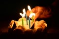 Anniversary cake with hand burning candles in dark