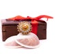 Anniversary gift concept. Cocktail golden ring on seashell and wooden gift box decorated with red ribbon on white background