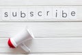 Announcement for subscribe with megaphone and text on white wooden background top view space for text