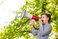 Announcing concept, boy shouting or screaming through the megaphone over forest background with copyspace Royalty Free Stock Photo