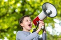 Announcing concept, boy shouting or screaming through the megaphone over forest background with copyspace Royalty Free Stock Photo