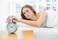 Annoyed beautiful woman turning off the alarm clock while lying in her bed Royalty Free Stock Photo