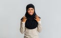 Annoyed black muslim woman emotionally gesturing with hands and grimacing