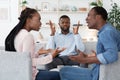 Annoyed black psychologist watching couple arguing during marital therapy session