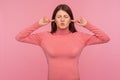 Annoyed brunette woman closing her eyes and ears with fingers, tired of bothersome loud sound, high decibel alarm Royalty Free Stock Photo