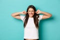 Annoyed brunette woman in white t-shirt, shut ears and frowning, cant stand awful noise or loud sound, standing bothered Royalty Free Stock Photo