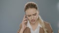 Annoyed business woman calling mobile phone on gray background Royalty Free Stock Photo