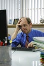 Annoyed businessman at desk looking at computer, vertical Royalty Free Stock Photo